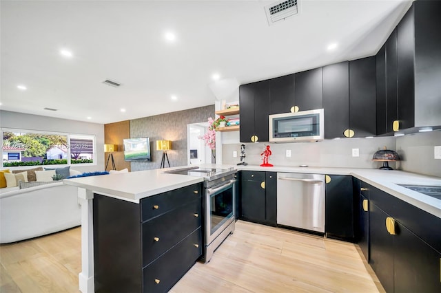 kitchen with visible vents, stainless steel appliances, dark cabinetry, and open floor plan