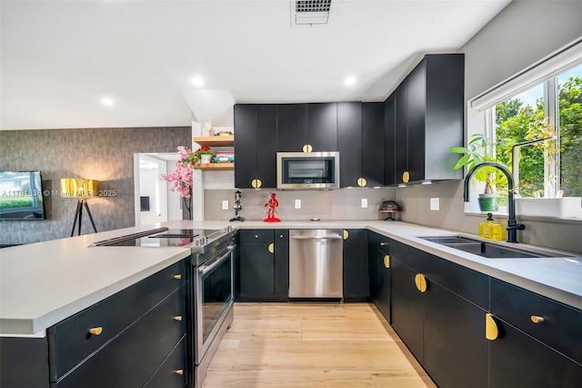 kitchen with visible vents, a sink, dark cabinetry, a peninsula, and appliances with stainless steel finishes