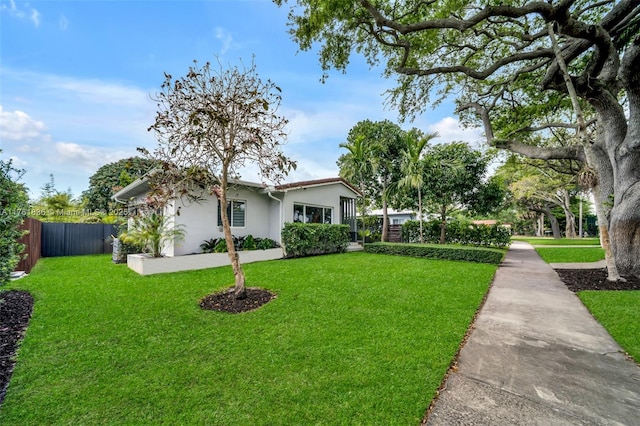 view of front of home with stucco siding, a front lawn, and fence