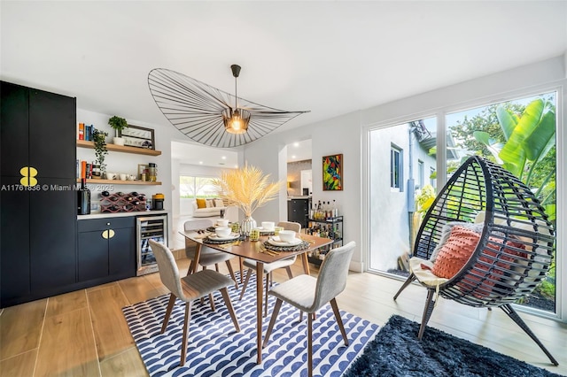 dining space featuring wine cooler, plenty of natural light, a dry bar, and light wood-type flooring