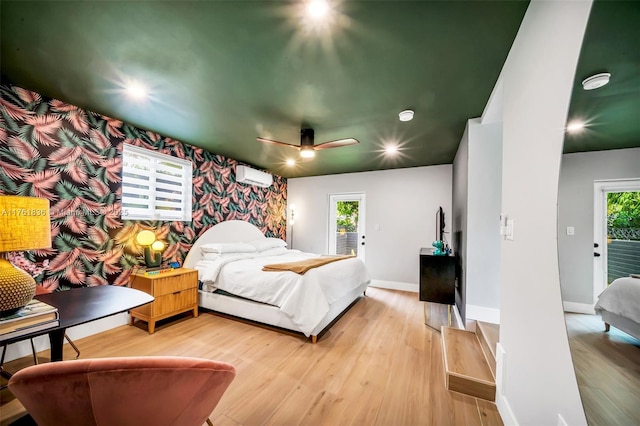 bedroom with baseboards, wallpapered walls, an AC wall unit, light wood-style floors, and an accent wall