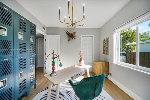 office featuring a notable chandelier, visible vents, light wood-style flooring, and baseboards