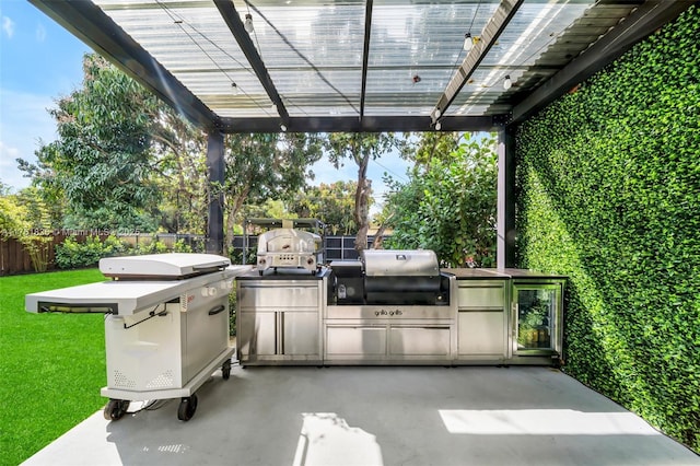 view of patio with area for grilling, fence, a pergola, and an outdoor kitchen