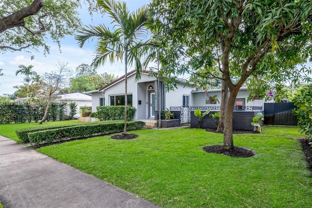 view of front of property featuring stucco siding, a front yard, and fence