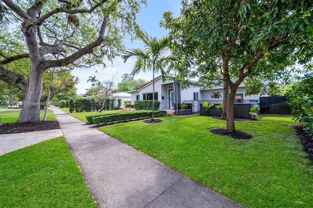 view of front of home featuring stucco siding, a front yard, and fence