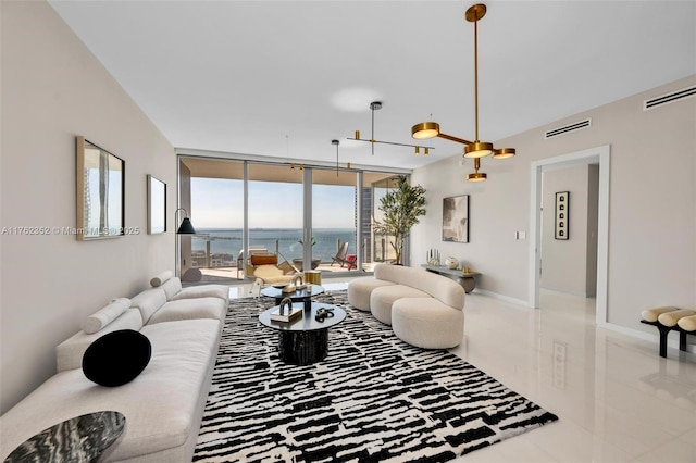 living room with a wall of windows, visible vents, baseboards, and a water view