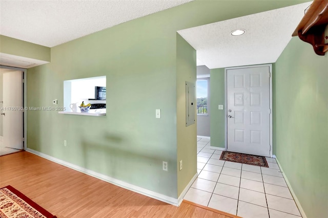 foyer entrance featuring light tile patterned floors, baseboards, and a textured ceiling