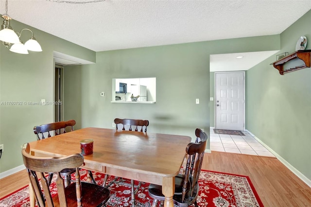 dining area with a chandelier, a textured ceiling, and light wood-style flooring