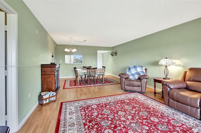 living area with baseboards, a notable chandelier, wood finished floors, and a textured ceiling