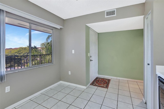 foyer featuring light tile patterned floors, baseboards, and visible vents