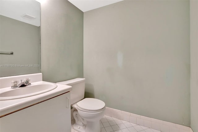 half bathroom featuring tile patterned flooring, visible vents, toilet, and vanity