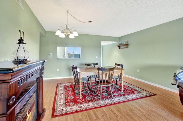 dining room featuring baseboards, a textured ceiling, and wood finished floors