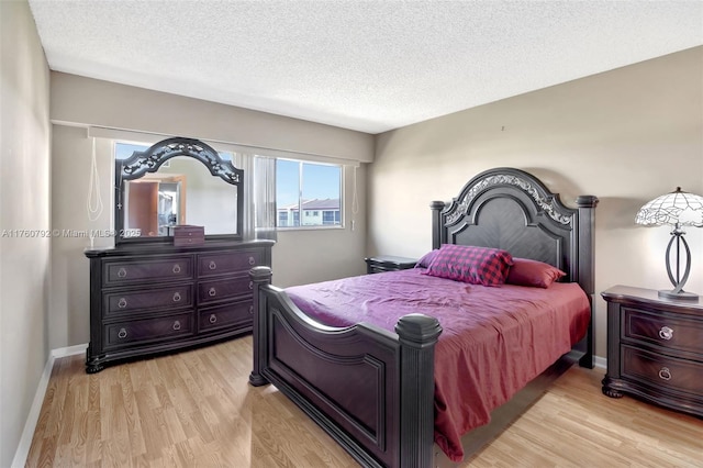 bedroom featuring baseboards, a textured ceiling, and light wood-style flooring