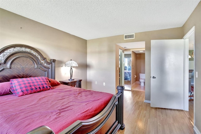 bedroom featuring light wood finished floors, visible vents, and a textured ceiling