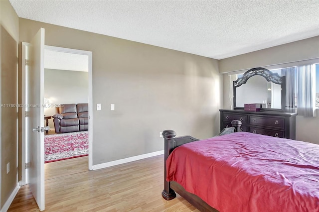 bedroom featuring light wood-style flooring, baseboards, and a textured ceiling