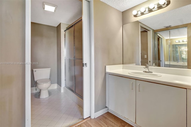 full bathroom featuring baseboards, toilet, a stall shower, a textured ceiling, and vanity