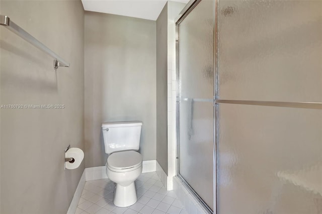 bathroom featuring tile patterned flooring, a stall shower, toilet, and baseboards