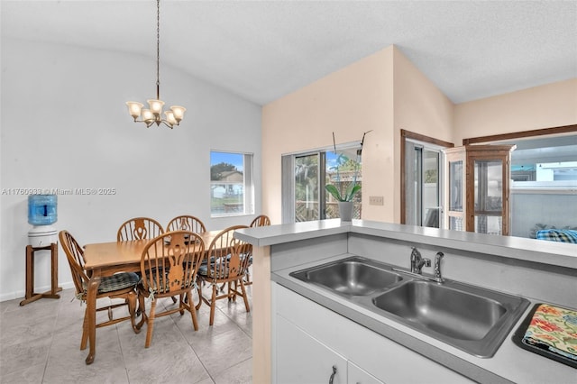 kitchen featuring lofted ceiling, a healthy amount of sunlight, a chandelier, and a sink