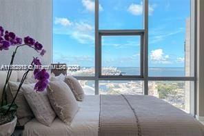 bedroom featuring floor to ceiling windows, multiple windows, and a water view