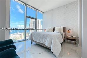 bedroom with a wall of windows and marble finish floor