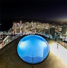 pool at night featuring a jacuzzi and a view of city lights