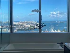 interior space with a bath, vanity, and a water view