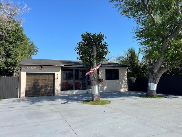 ranch-style home with fence, a garage, driveway, and stucco siding