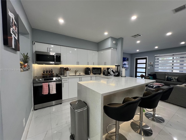 kitchen featuring stainless steel appliances, marble finish floor, visible vents, and a breakfast bar