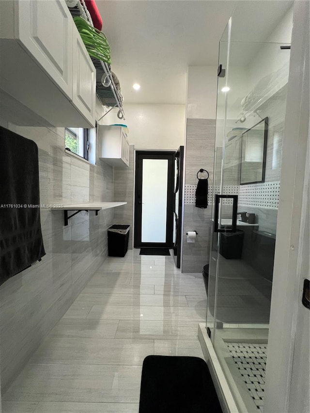 bathroom with tile walls and a shower stall