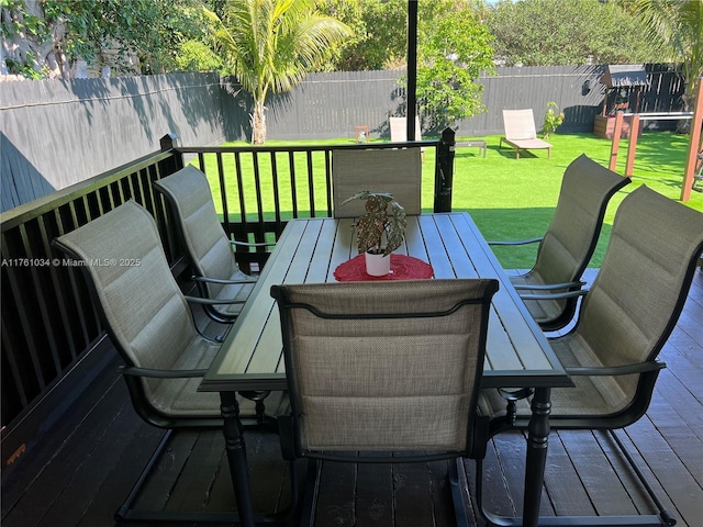 wooden deck with outdoor dining area, a lawn, and a fenced backyard