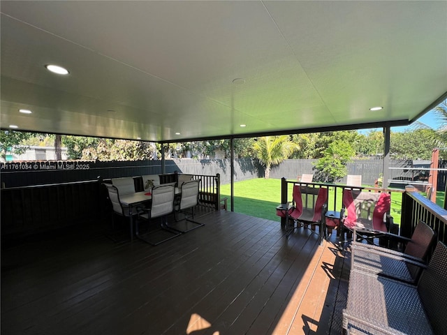 wooden deck with outdoor dining space, a lawn, and a fenced backyard