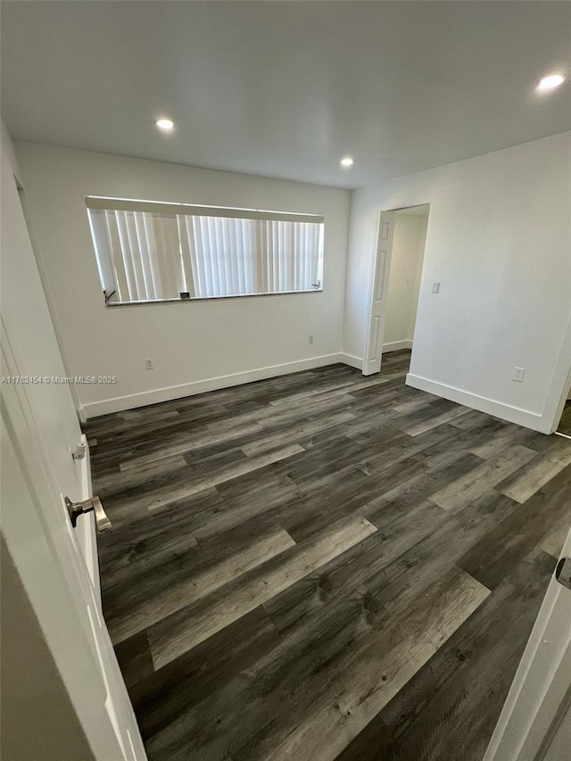 spare room featuring dark wood finished floors, recessed lighting, and baseboards