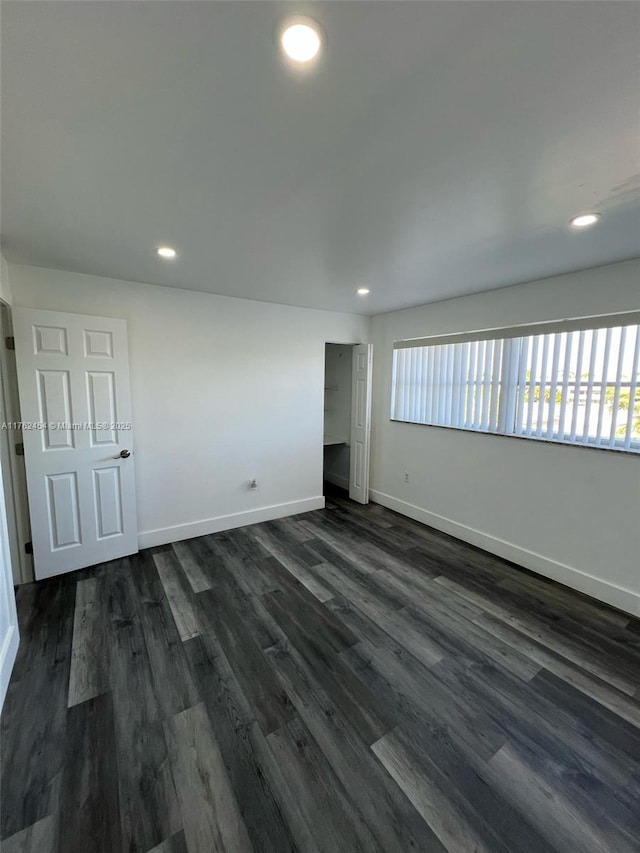 unfurnished room featuring recessed lighting, dark wood-style floors, and baseboards