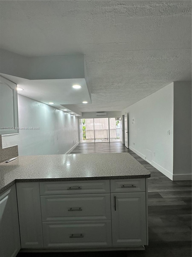 kitchen featuring dark wood-type flooring, white cabinets, baseboards, and a textured ceiling