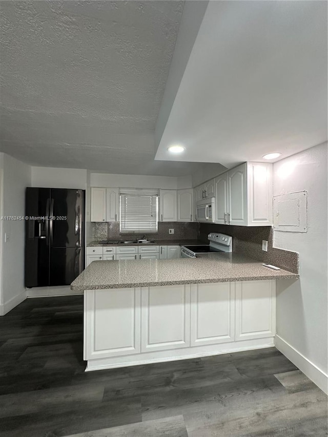 kitchen with white microwave, a peninsula, range with electric cooktop, decorative backsplash, and black refrigerator with ice dispenser