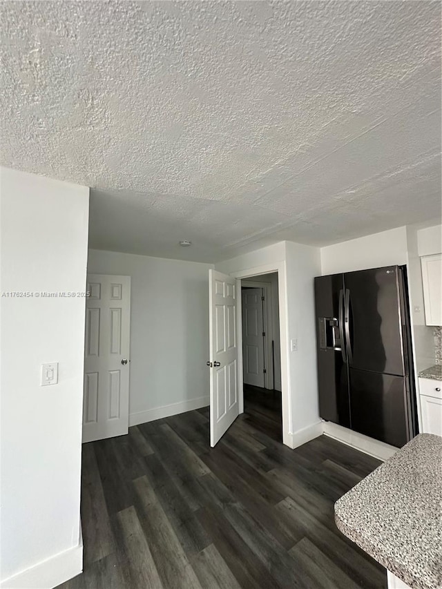 interior space featuring baseboards, a textured ceiling, and dark wood-style floors