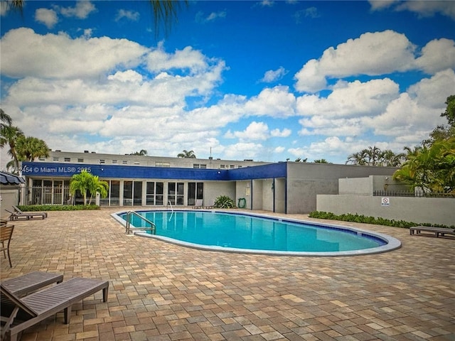 community pool with a patio area and fence