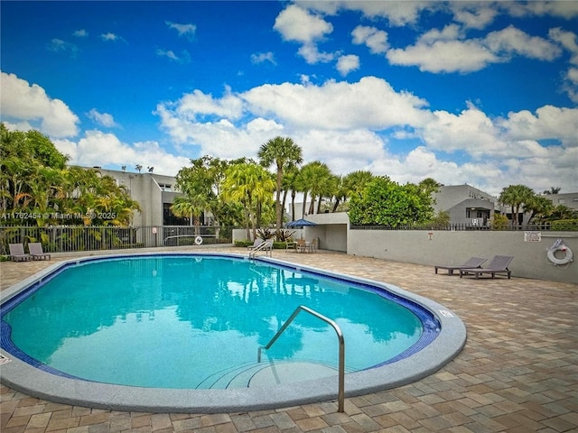 community pool with a patio and fence