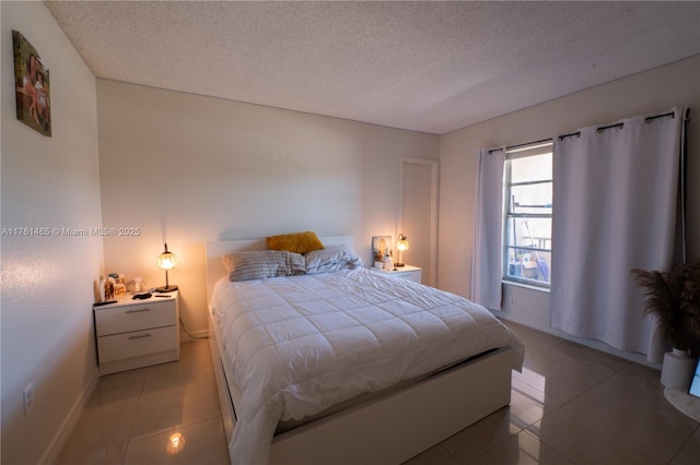 bedroom with light tile patterned floors, a textured ceiling, and baseboards