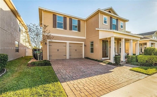 view of front of house with a front yard, decorative driveway, a garage, and stucco siding