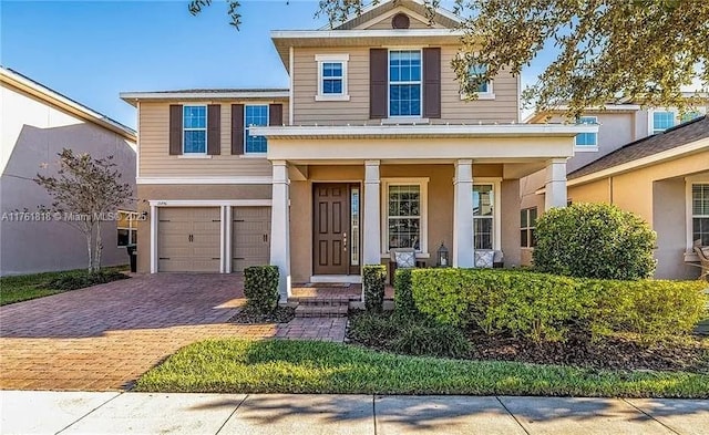 traditional home featuring a porch, decorative driveway, an attached garage, and stucco siding