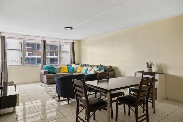 dining space featuring light tile patterned flooring, baseboards, and a textured ceiling