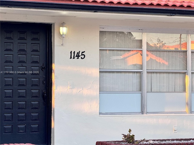 doorway to property featuring a tiled roof and stucco siding