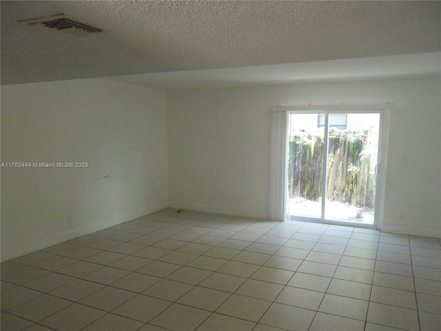 spare room with light tile patterned flooring, baseboards, visible vents, and a textured ceiling