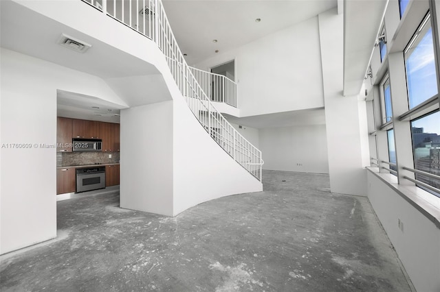 1395 Brickell Ave Unit 3403, Miami, FL 33131 - unfurnished living room with visible vents, a towering ceiling, and stairway