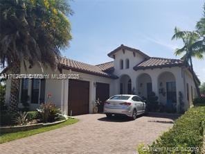 mediterranean / spanish-style house featuring a tiled roof, decorative driveway, and a garage