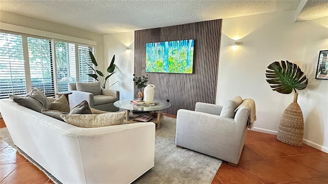 living area with tile patterned floors, a textured ceiling, an accent wall, and baseboards