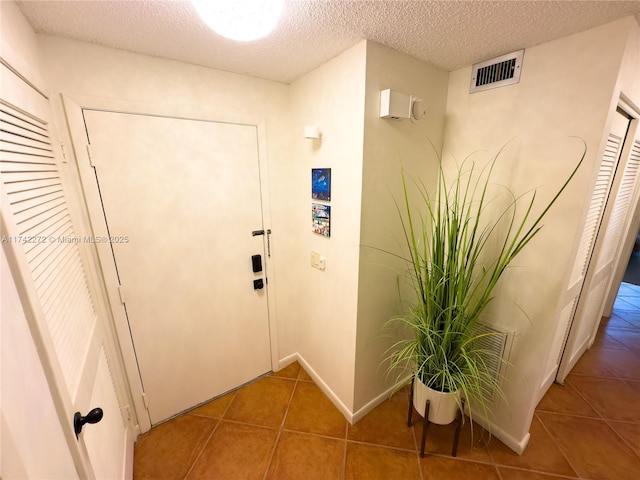 interior space with tile patterned floors, baseboards, visible vents, and a textured ceiling