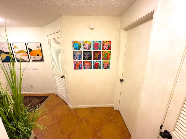 hall featuring tile patterned floors, baseboards, and a textured ceiling