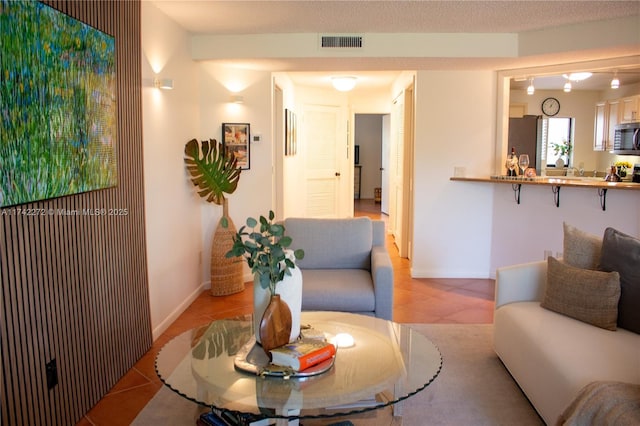 living area featuring light tile patterned floors, visible vents, and baseboards